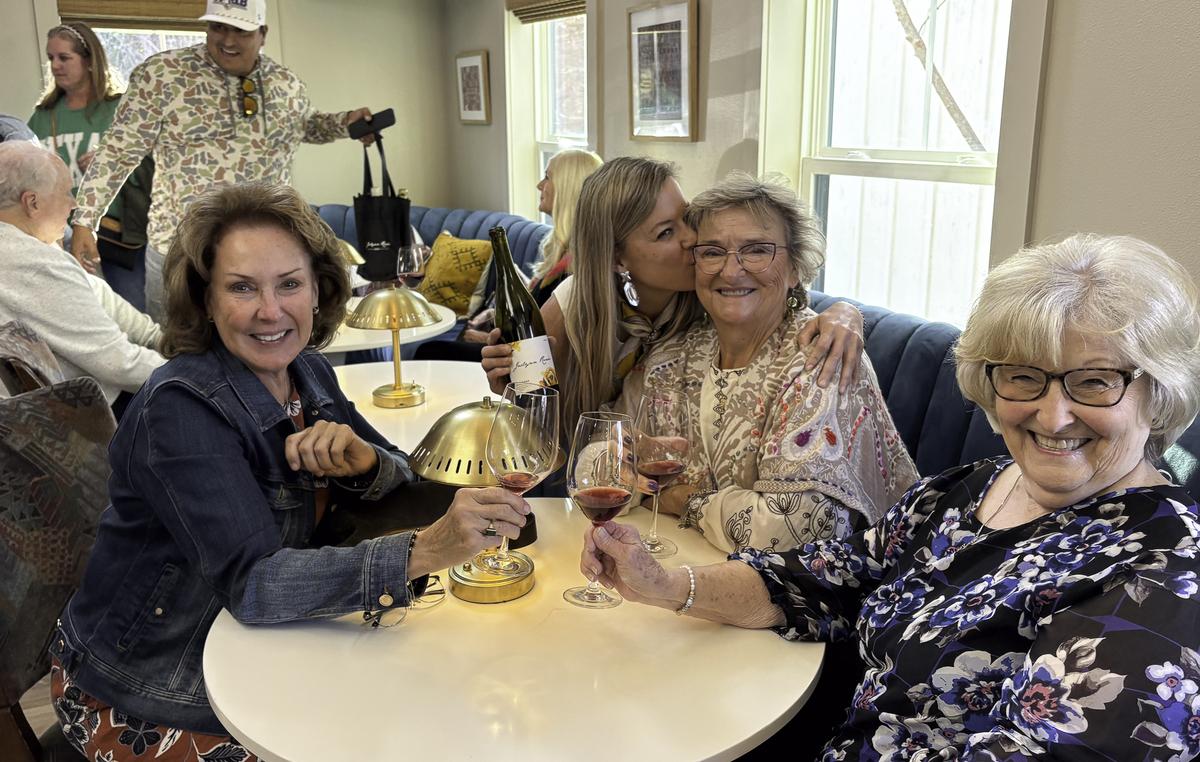 At a table of long-time friends, Jackie plants an affectionate kiss on Patty...