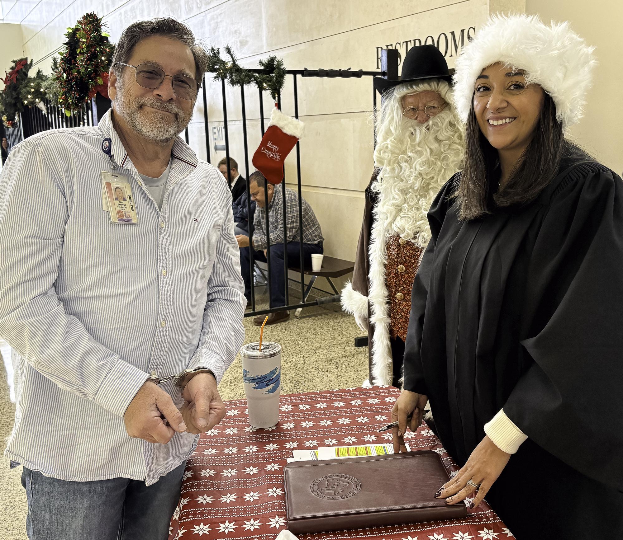 Justice of the Peace Maggie Moreno, right, charges EMS Director Ken Strange,...